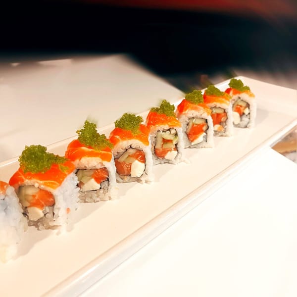 Kameya Sushi's salmon rolls with green tobiko, cream cheese, and cucumber on a white plate.